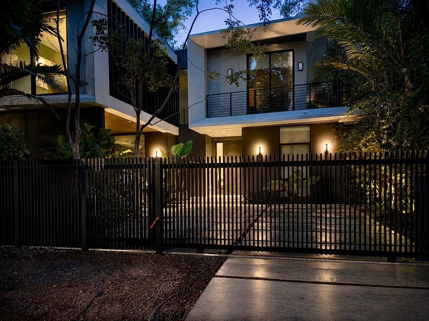 Modern luxury home with custom black slat gate at twilight
